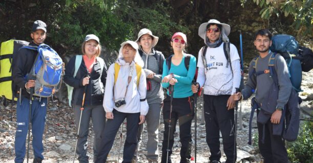 A collection of individuals with backpacks pauses on a scenic trail, surrounded by nature and enjoying the outdoors.