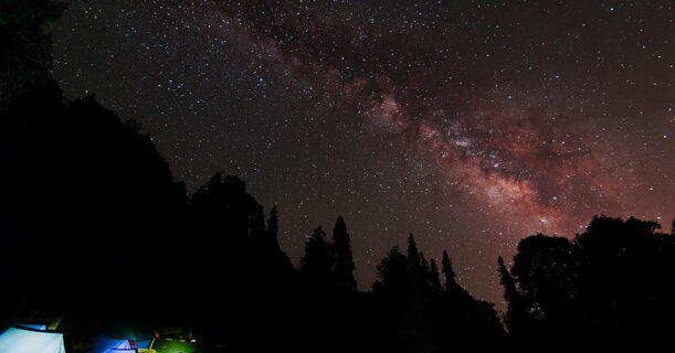 A glowing tent under a starry night sky.