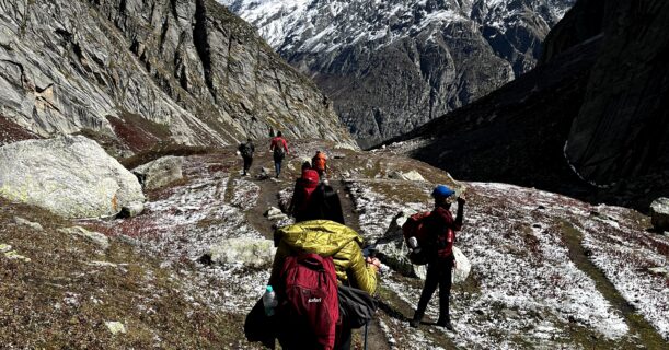 Trekkers walking on a mountain trail with snow covered Himalayan peaks