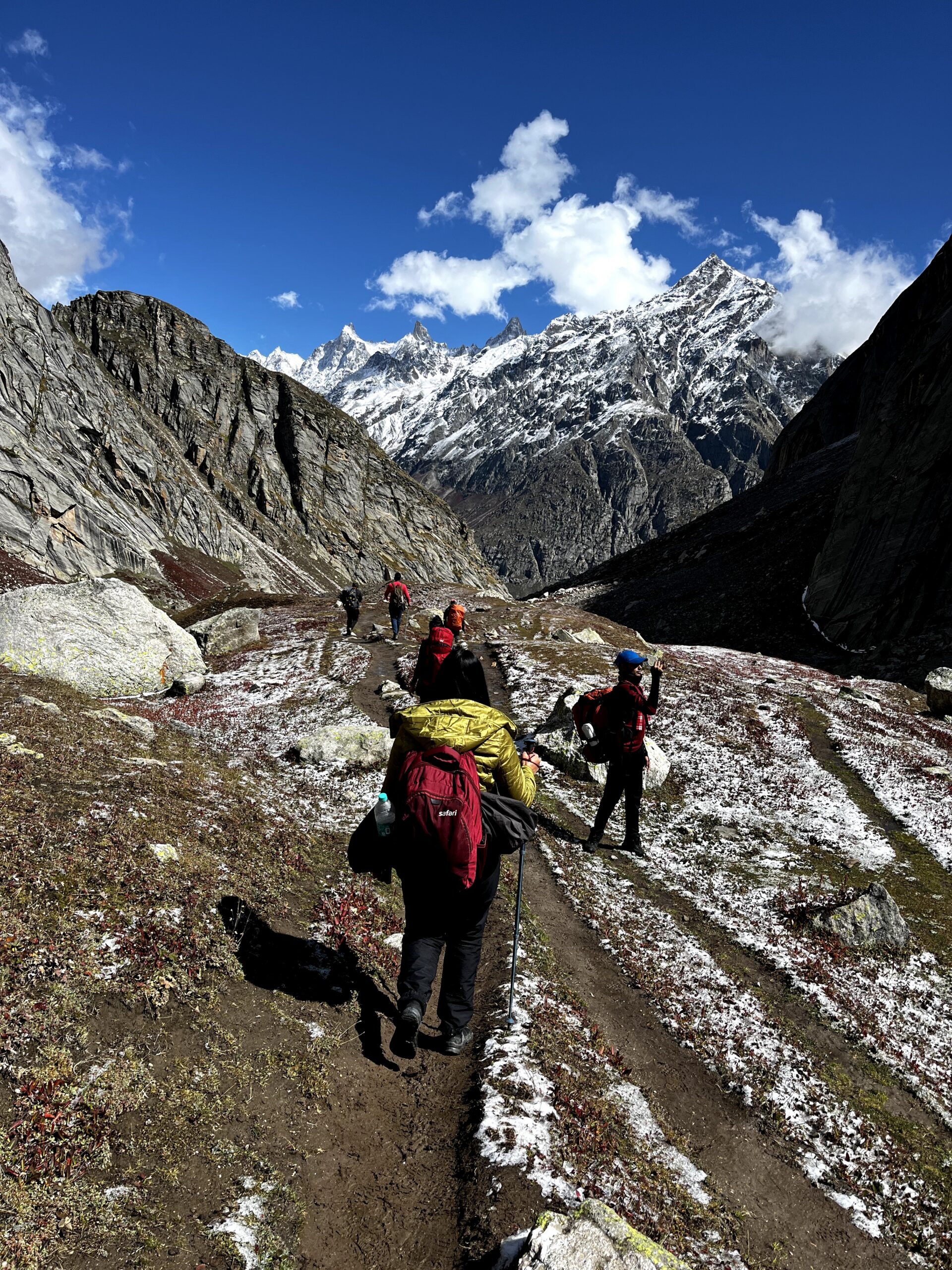 Trekkers walking on a mountain trail with snow covered Himalayan peaks