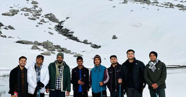 Men gathered in front of a stunning mountain landscape.