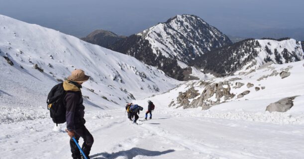 People hike up snowy mountains with skis and enjoy outdoor winter activities.