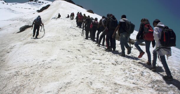 Several trekkers trekked up a snow-covered mountain, showcasing determination against a backdrop of white peaks.