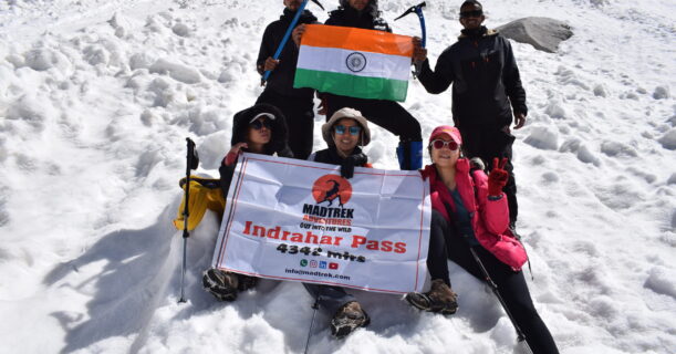 Smiling group of friends posing for a picture at the mountain peak.