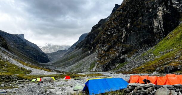 Hikers trekking through the Himalayan mountains with camping tents and snow-covered peaks