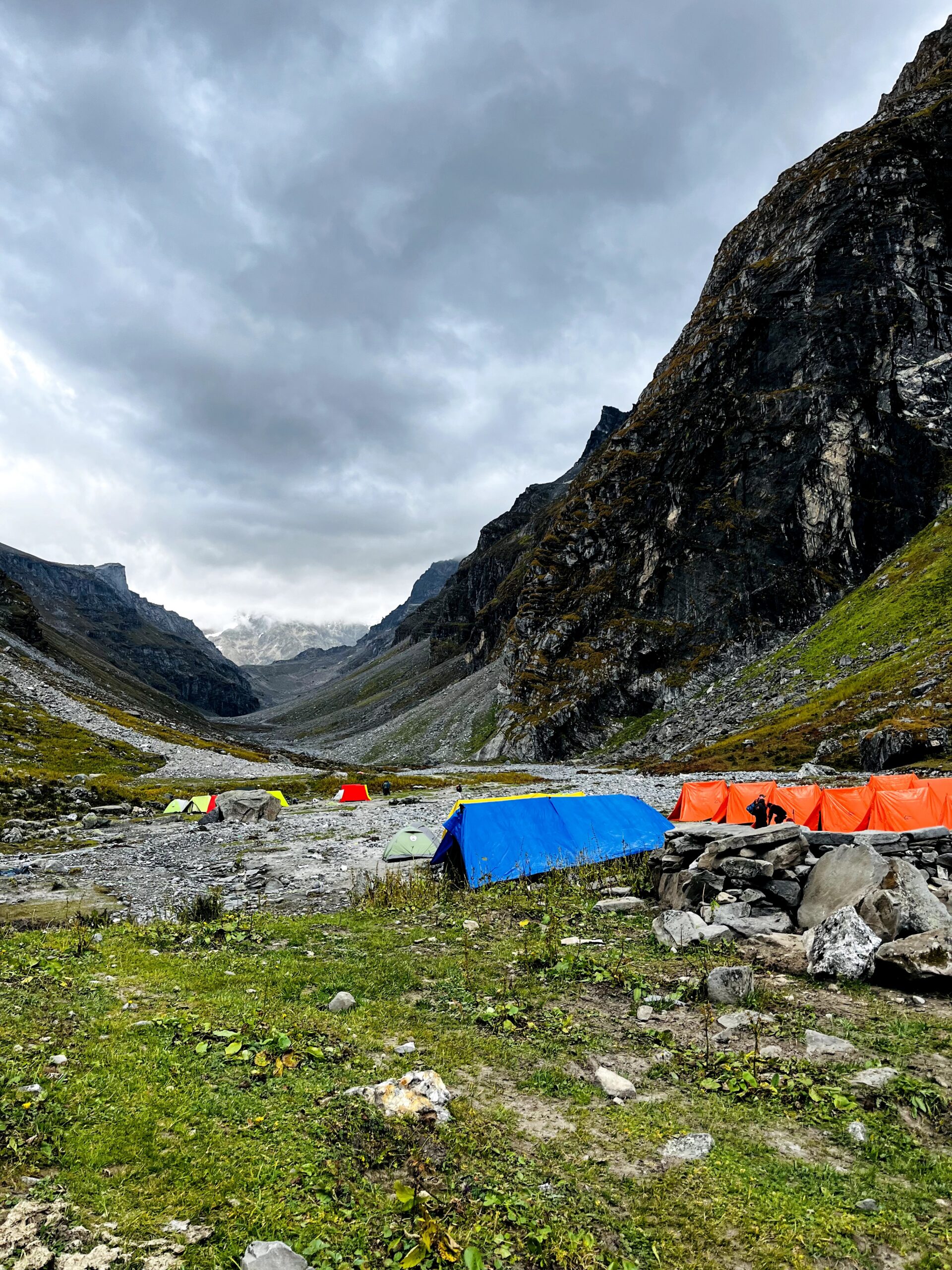 Hikers trekking through the Himalayan mountains with camping tents and snow-covered peaks