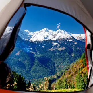 A breathtaking view of mountains seen through the open flap of a cozy tent in the wilderness