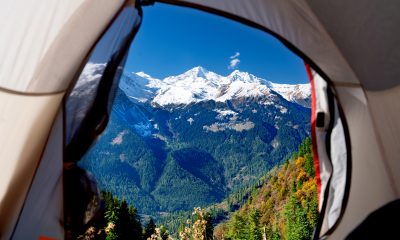 A breathtaking view of mountains seen through the open flap of a cozy tent in the wilderness