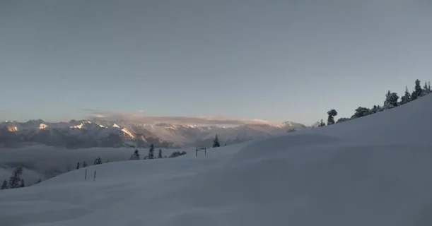 A person skiing on a snow-covered slope with mountains in view.