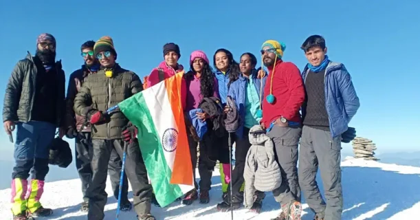 Friends taking a picture together at the peak of a mountain.