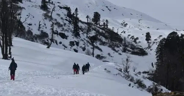 Numerous trekkers navigate through the snowy mountain terrain