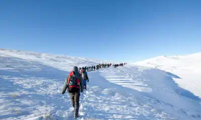 Some individuals trekking up a snow-covered mountain, surrounded by a winter wonderland.