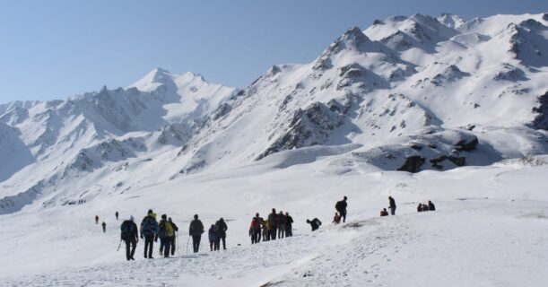 A collection of trekkers trekking up a snow-covered mountain.