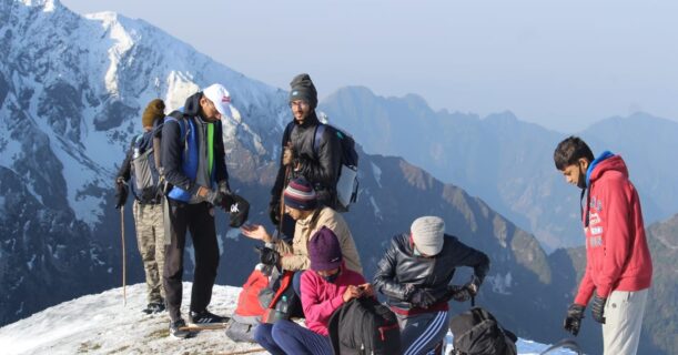 A diverse group of individuals standing triumphantly on a mountain peak, enjoying the breathtaking view around them.