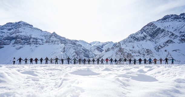 People holding hands as a sign of peace with the mountains in the background in winter