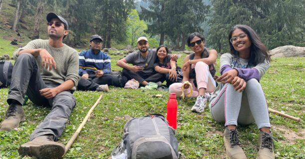 Friends are sitting on the grass in the mountains, enjoying nature.