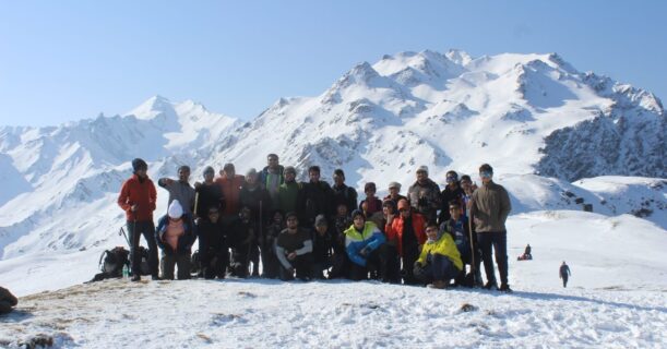 Team standing on a snowy mountain peak.