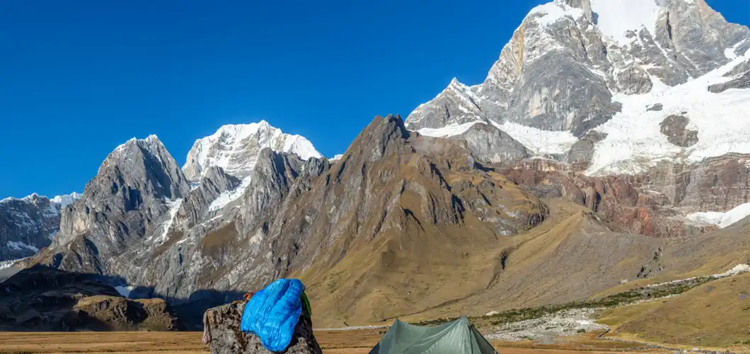 A tent pitched in front of majestic mountains.