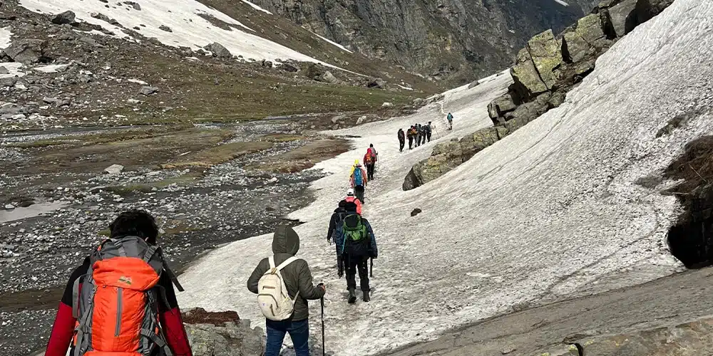 a group of trekkers, equipped with backpacks and trekking poles crossing hampta pass