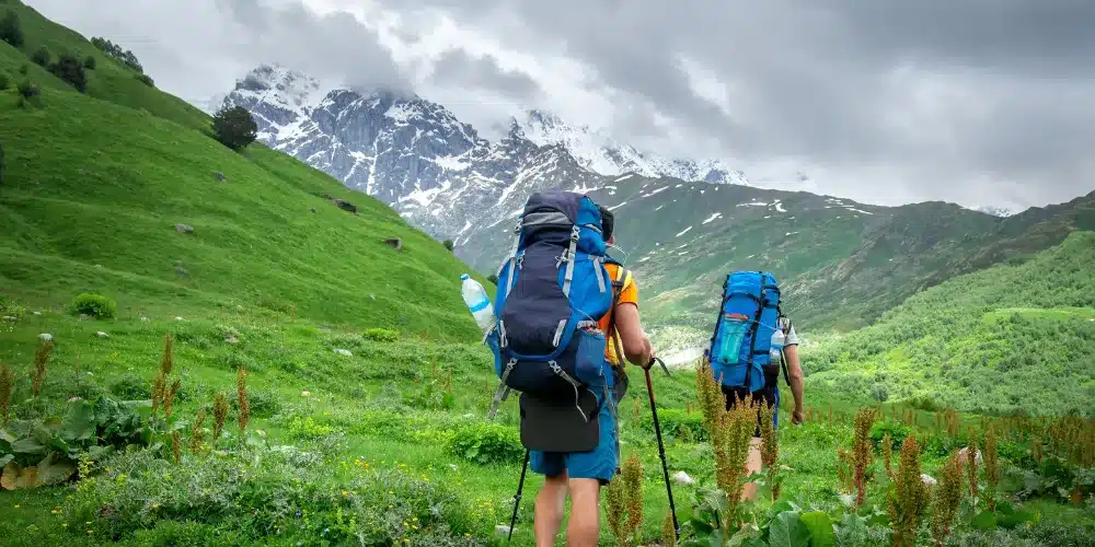 Two Travelers Equipped with Backpacks and Trekking Poles Trekking During Monsoon