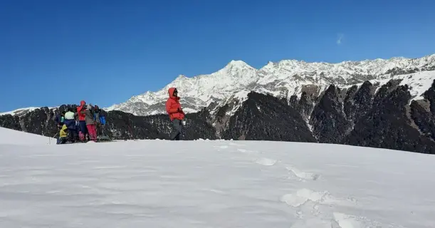 Trekkers walking on snow trail with Himalayan peaks