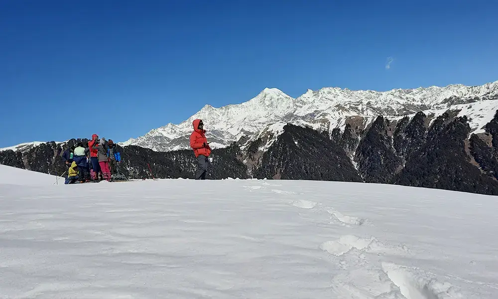 Trekkers walking on snow trail with Himalayan peaks