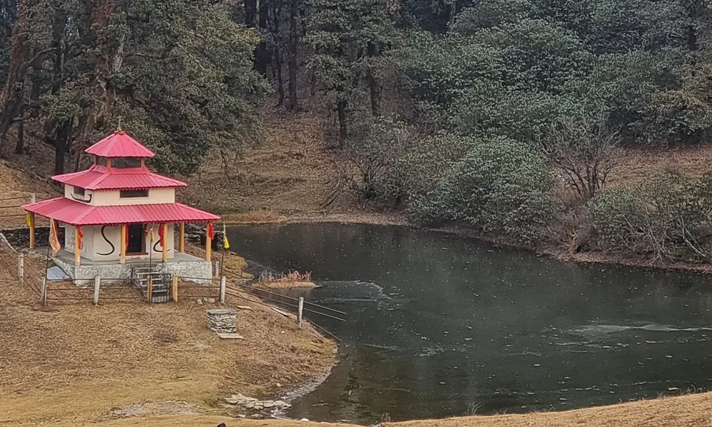 Small Hindu temple near forested lake on trekking route