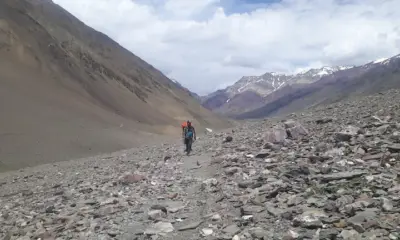 Trekkers walking through a barren, rocky trail in Pin Valley after crossing Pin Parvati Pass.