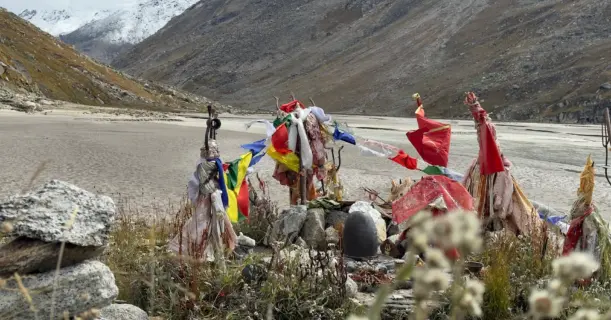 Close-up of sacred prayer flags and Shiva lingam at Mantalai Lake during the Pin Parvati Pass Trek in Himachal Pradesh