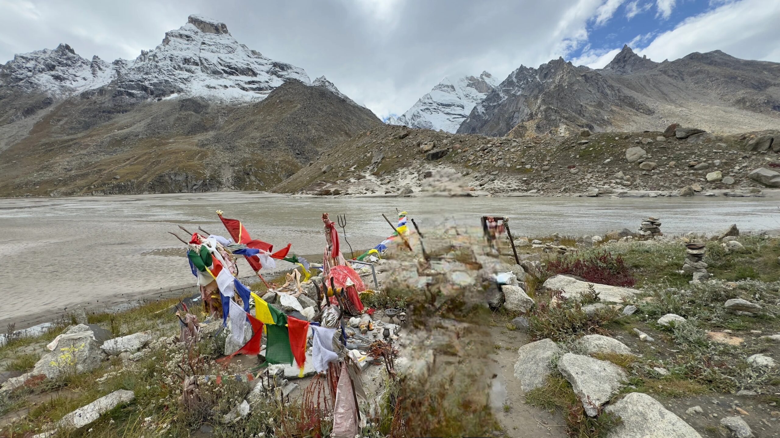 Mantalai Lake on the Pin Parvati Pass Trek, with prayer flags and snow-capped Himalayan peaks in Parvati Valley, Himachal Pradesh
