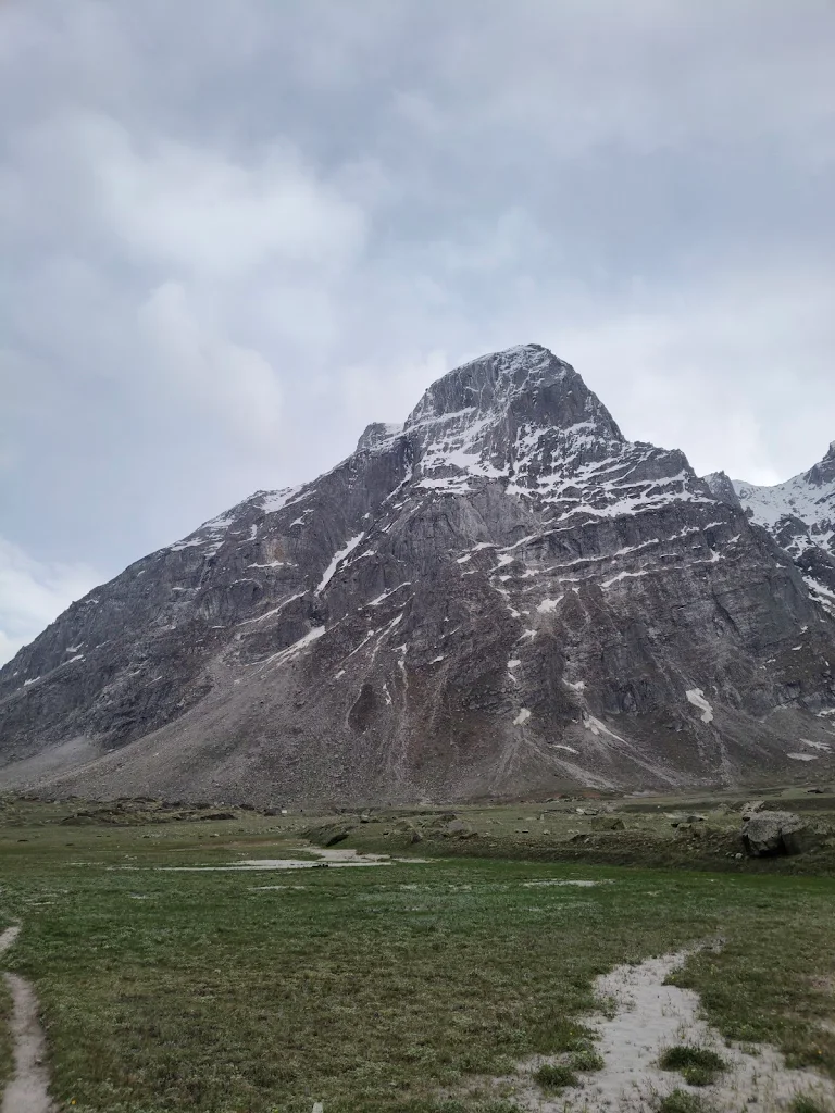 Odi Thach campsite with a towering rocky mountain in the background on the Pin Parvati Pass trek.