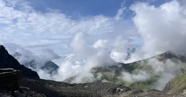 View from near Pin Bhabha Pass summit showing dramatic cloudscape over deep valleys and rugged terrain.