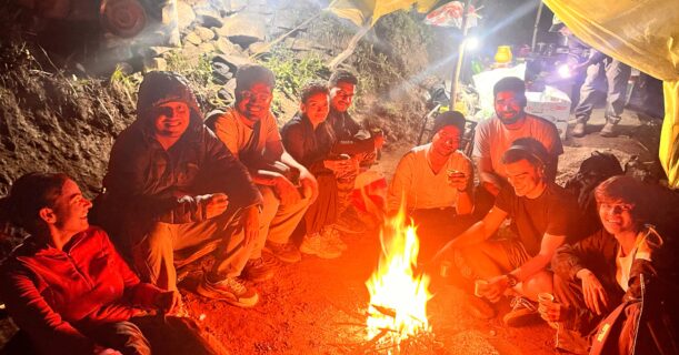 Group of trekkers enjoying a warm campfire at Yulla Kanda Base Camp during night stay in Himachal Pradesh