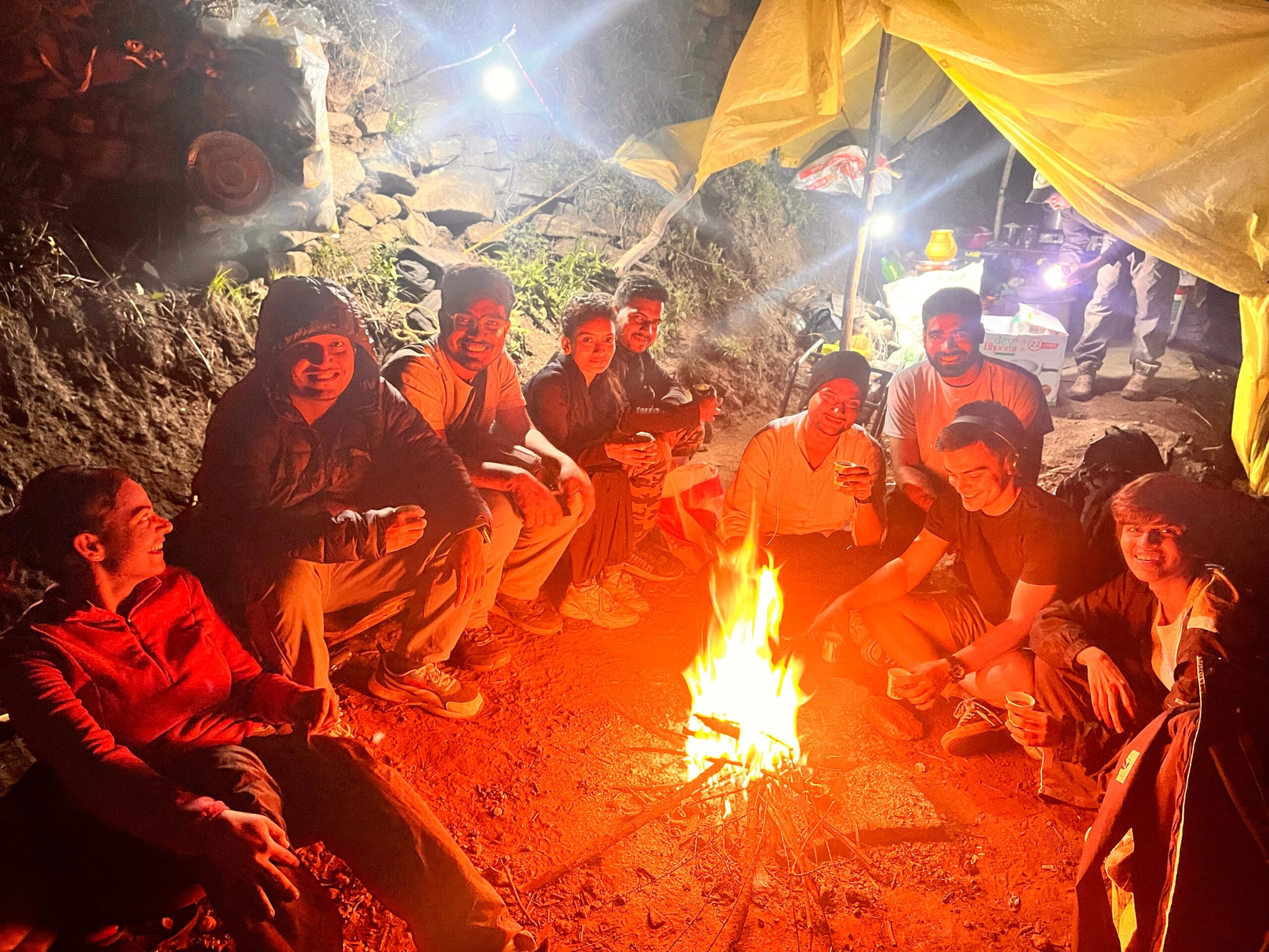 Group of trekkers enjoying a warm campfire at Yulla Kanda Base Camp during night stay in Himachal Pradesh