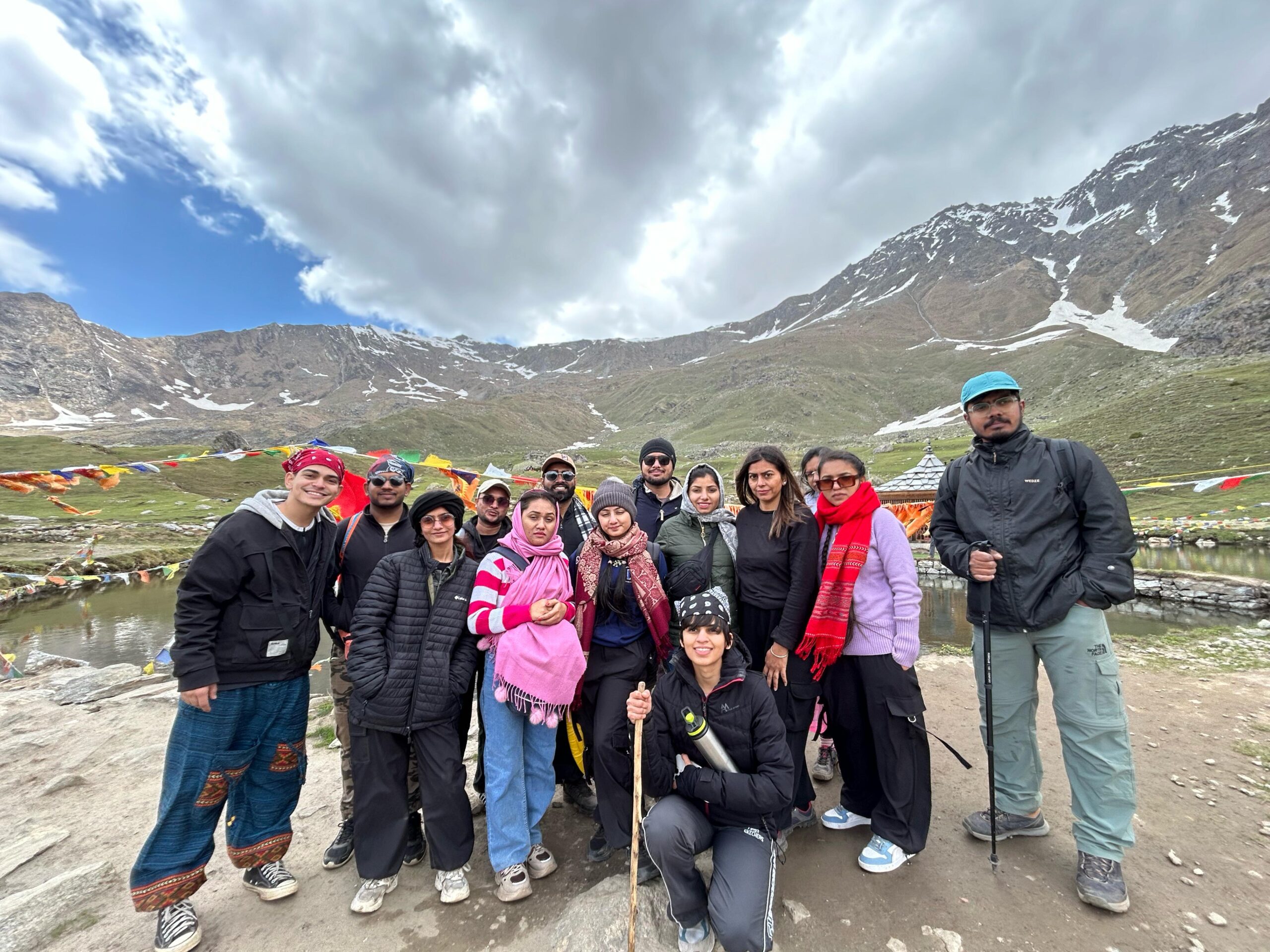 Travelers resting at Yulla Kanda Lake during a Himalayan trek in Kinnaur Valley