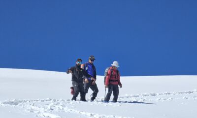 Trekkers ascending the snow ridge during Pangarchulla Peak Trek in Uttarakhand under a clear blue sky.