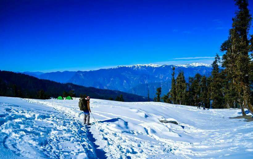 Person walking on snow with mountains